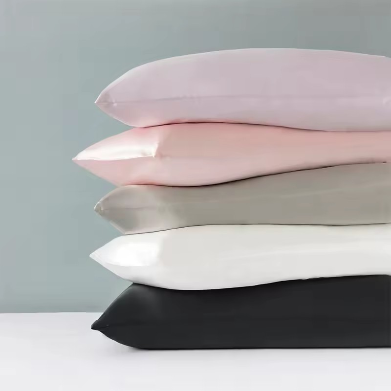 Stack of four pillows in pink, gray, white, and black on a light gray background