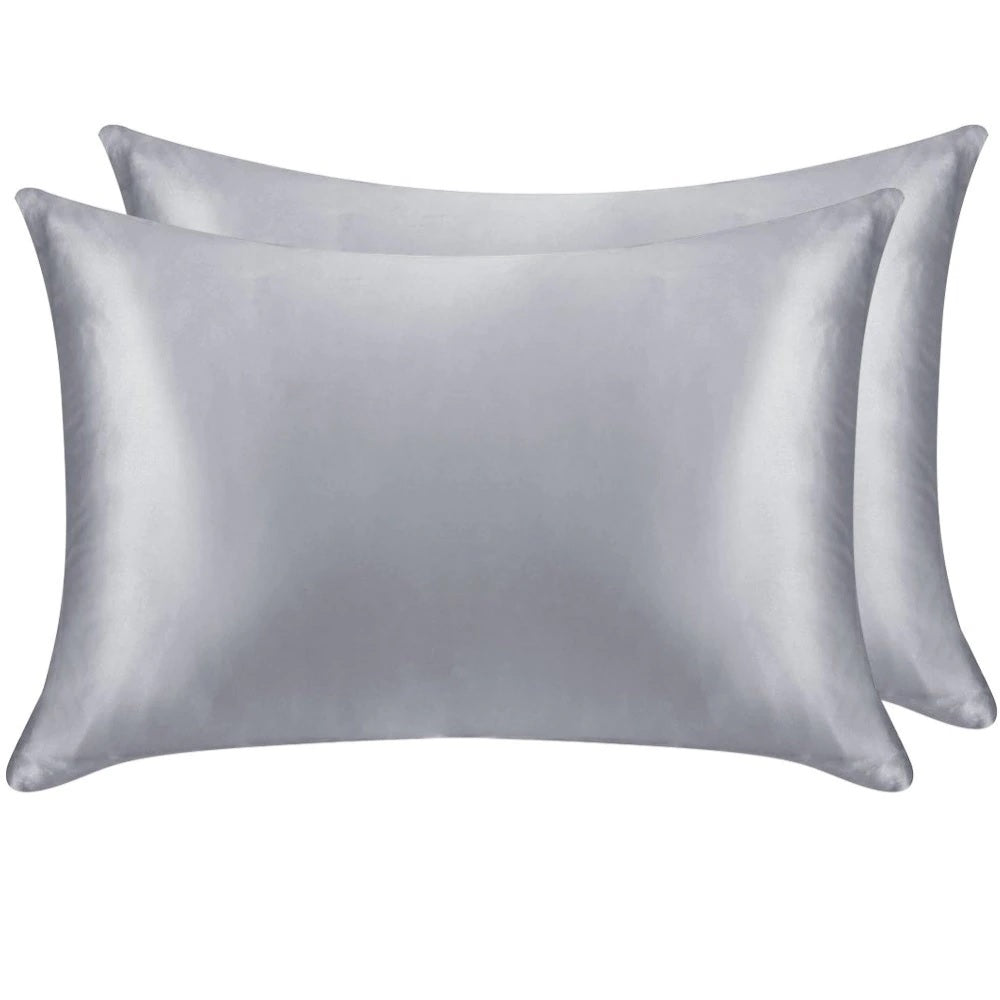 Two silver satin pillowcases on a white background