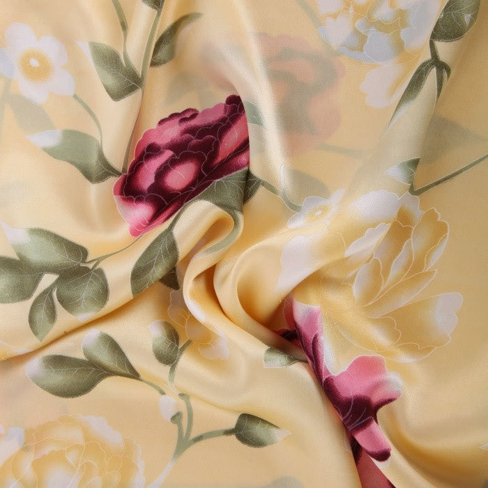 Floral fabric with pink roses and green leaves on a yellow background