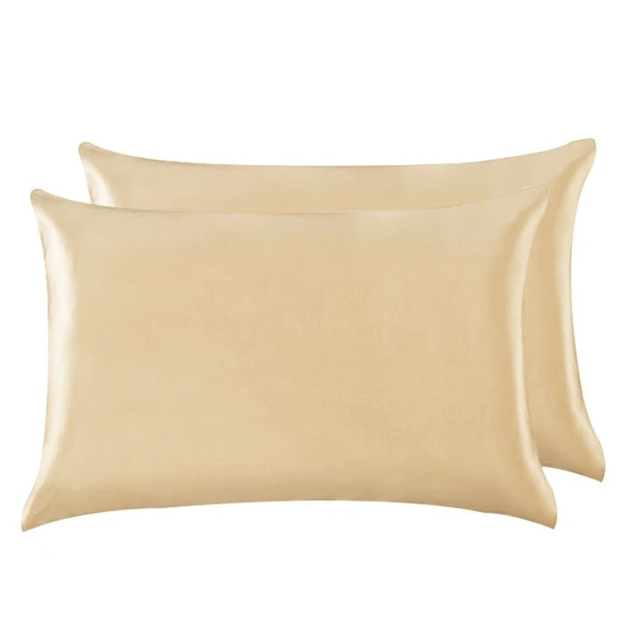 Two beige satin pillowcases on a white background