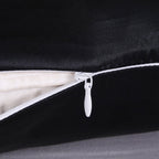 Close-up of a black pillow with a white zipper on a dark background