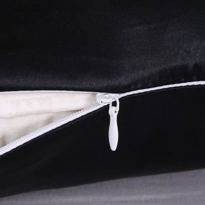 Close-up of a black pillow with a white zipper on a dark background